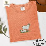 Terracotta Comfort Colors T-shirt embroidered with a woolly white ewe standing over her lamb resting on green grass