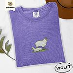 Violet Comfort Colors T-shirt embroidered with a woolly white ewe standing over her lamb resting on green grass