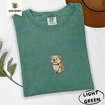 Light Green Comfort Colors T-shirt embroidered with a fawn and cream English bulldog puppy in a red collar chewing a string of Christmas lights