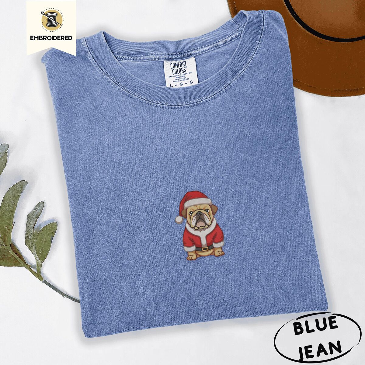 English Bulldog Santa Shirt – Blue Jean Blue Jean Comfort Colors T-shirt embroidered with a fawn English bulldog in a red Santa suit, black belt and Santa hat