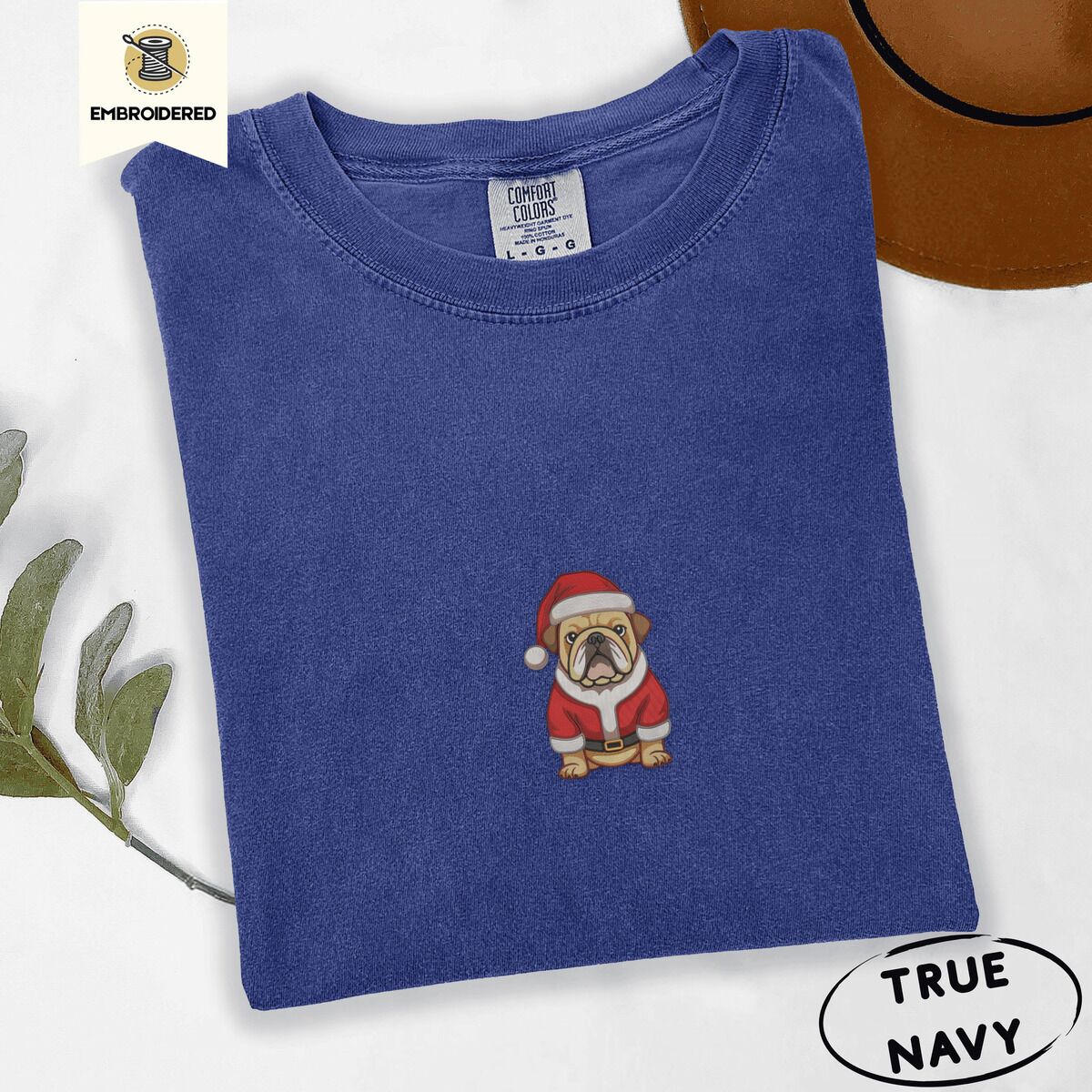 English Bulldog Santa Shirt – True Navy True Navy Comfort Colors T-shirt embroidered with a fawn English bulldog in a red Santa suit, black belt and Santa hat