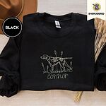 Black crewneck sweatshirt with a brown felt hat and dried bunny tail grass, embroidered with a liver and white English pointer on point among cattails and grass, with an optional name stitched below