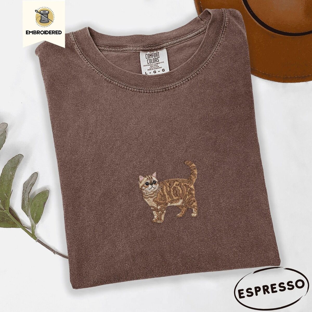 Exotic Shorthair Shirt – Espresso Espresso Comfort Colors T-shirt embroidered with an orange tabby Exotic Shorthair cat standing in profile with a flat face, round black eyes and a curled tail