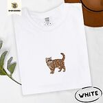 White Comfort Colors T-shirt embroidered with an orange tabby Exotic Shorthair cat standing in profile with a flat face, round black eyes and a curled tail