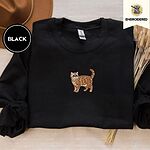 Black Exotic Shorthair sweatshirt with a brown felt hat and dried bunny tail grass, with a mini embroidered orange tabby cat centered on the chest