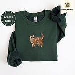 Forest Green Exotic Shorthair sweatshirt folded on a white background, with a mini embroidered orange tabby cat centered on the chest