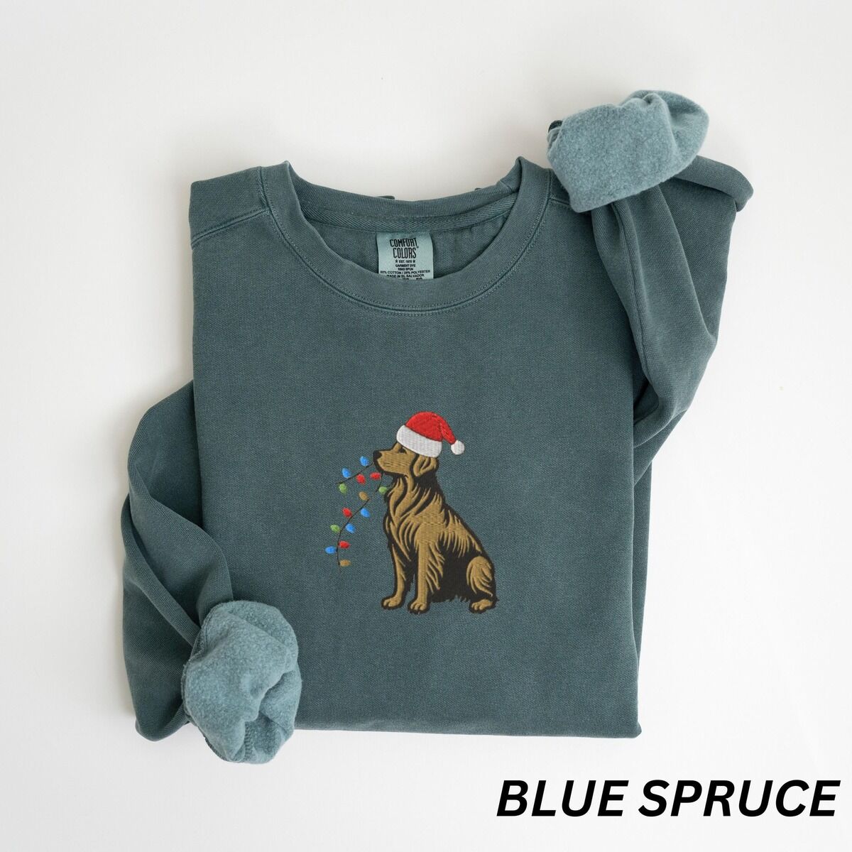 Festive Golden Retriever Sweatshirt – Blue Spruce Blue Spruce crewneck sweatshirt laid flat, embroidered with a sitting golden retriever in a Santa hat holding Christmas lights