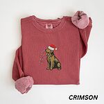 Crimson crewneck sweatshirt laid flat, embroidered with a sitting golden retriever in a Santa hat holding a strand of Christmas lights
