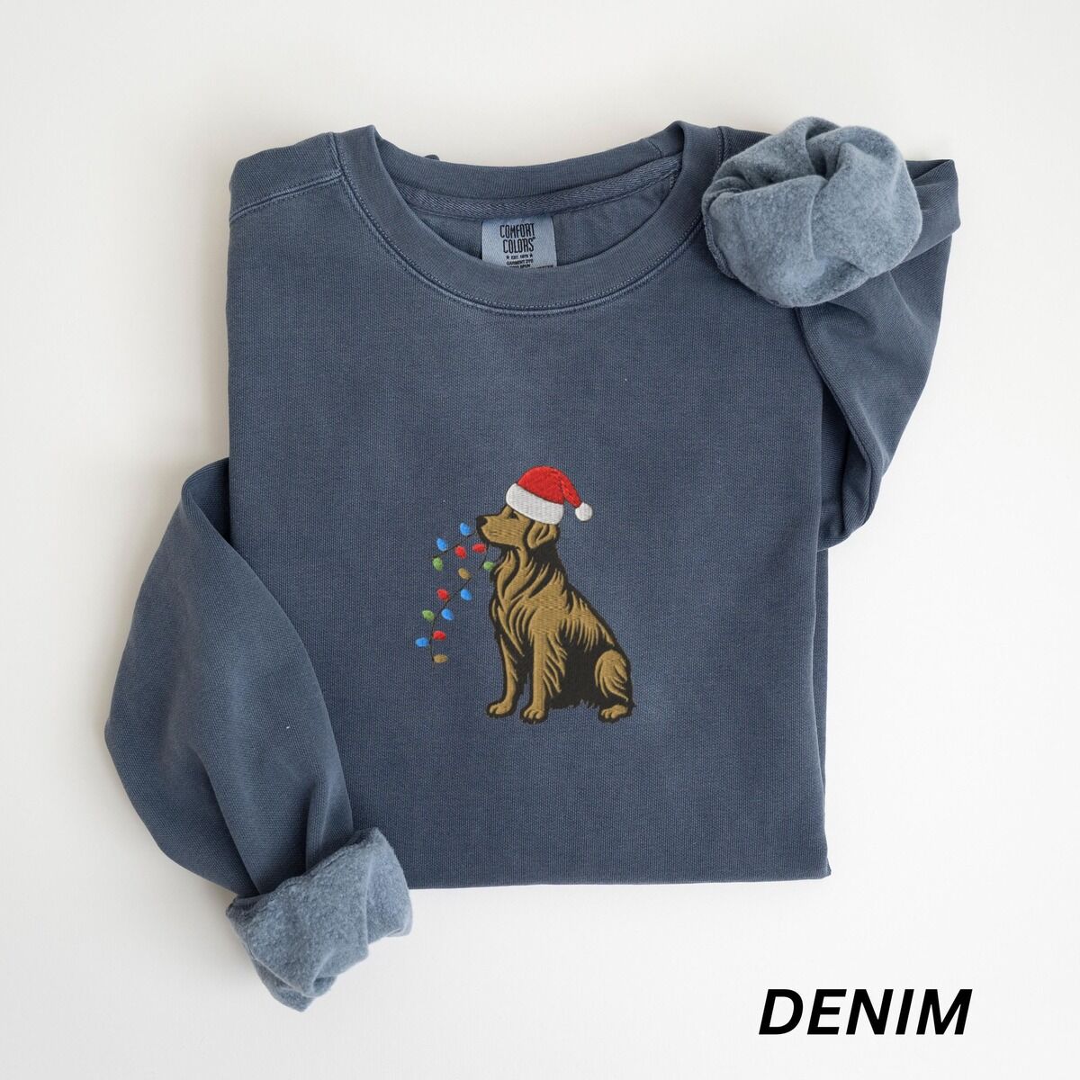 Festive Golden Retriever Sweatshirt – Denim Denim crewneck sweatshirt laid flat, embroidered with a golden retriever in a Santa hat with a light strand in its mouth