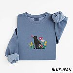 Blue Jean crewneck sweatshirt laid flat on white, embroidered with a sitting black Labrador silhouette among yellow bell flowers, a white tulip and pink daisies, with a pink butterfly