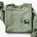Military Green crewneck sweatshirt laid flat on white, embroidered with a black dachshund silhouette standing among purple, yellow and white wildflowers on the left chest