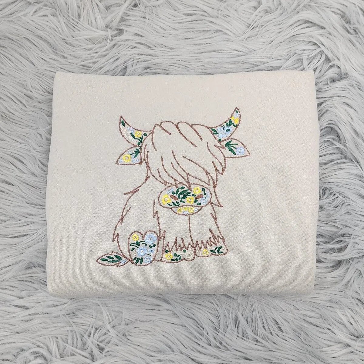 Floral Highland Cow Sweatshirt – Sand Floral Highland cow sweatshirt in Sand with a brown cow outline filled with yellow and blue wildflowers