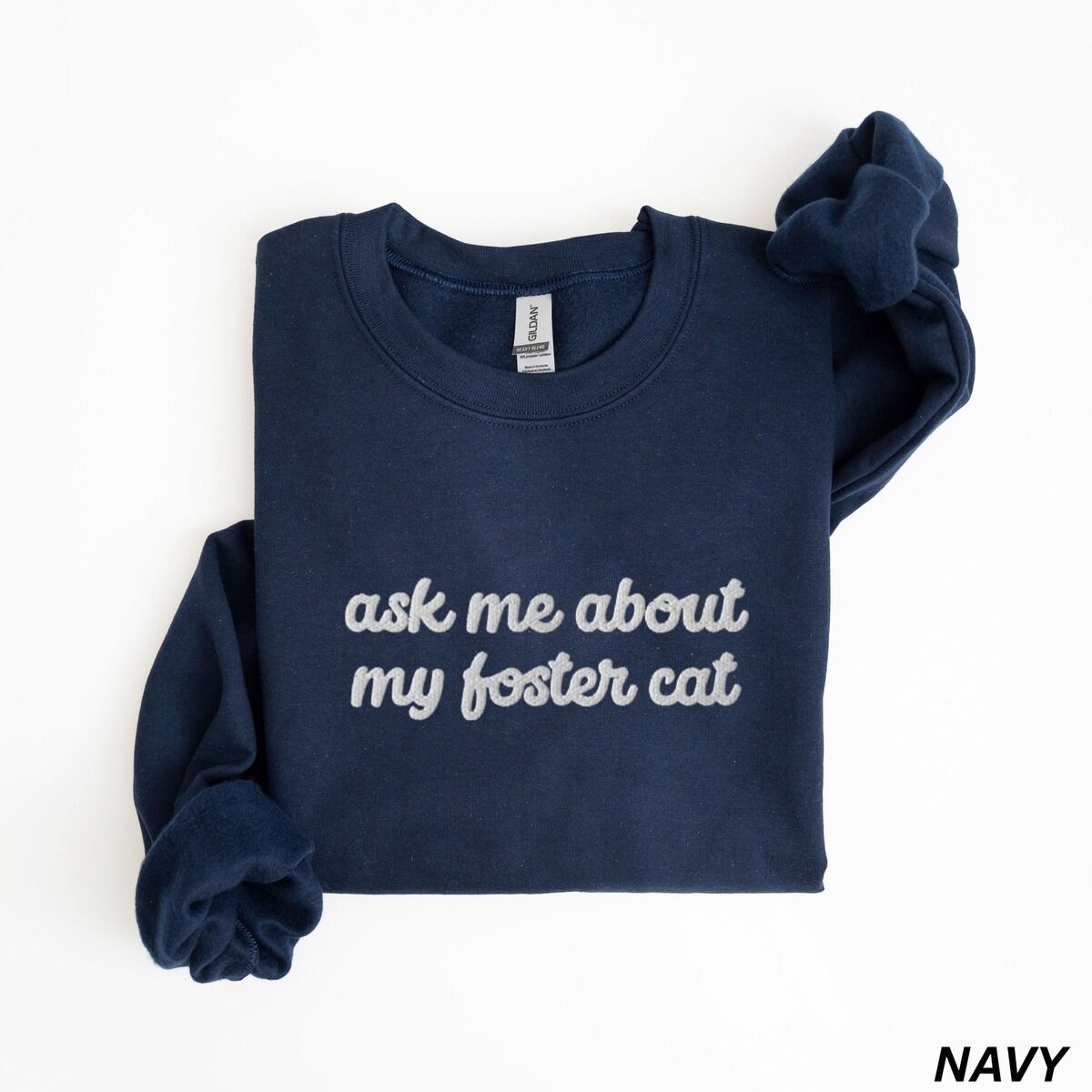 Foster Cat Sweatshirt – Navy Navy crewneck sweatshirt folded on a white background, with the words ask me about my foster cat embroidered in cursive across the chest in white thread