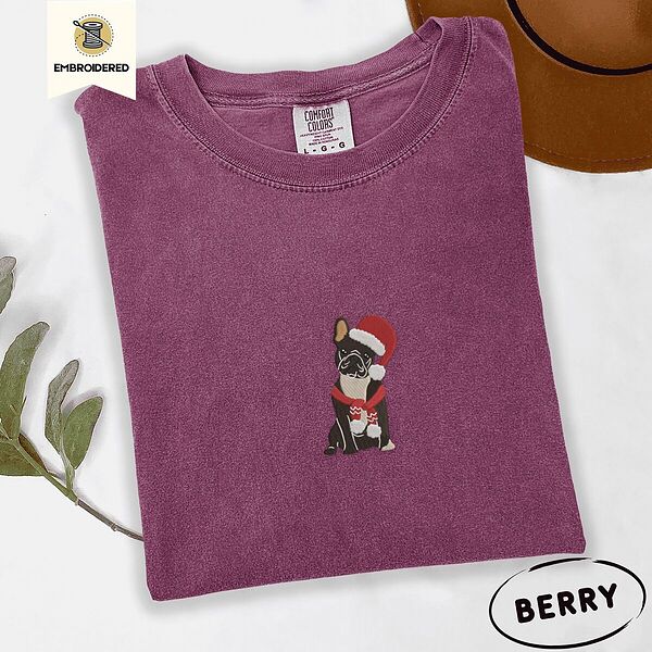 Berry Comfort Colors T-shirt embroidered with a black French bulldog with a cream chest in a Santa hat and a red scarf with white zigzag stripes