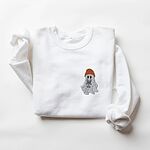 White crewneck sweatshirt laid flat on a white background, embroidered with a little ghost in a rust knit beanie hugging a grey French bulldog on the left chest