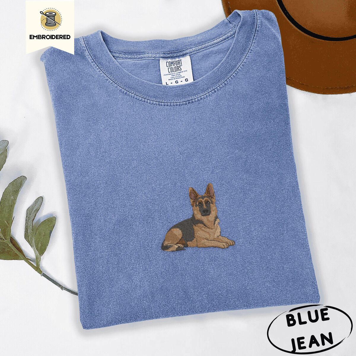 German Shepherd Shirt – Blue Jean Blue Jean Comfort Colors T-shirt embroidered with a black and tan German shepherd lying down with its ears up and its paws forward