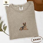 Khaki Comfort Colors T-shirt embroidered with a black and tan German shepherd lying down with its ears up and its paws forward