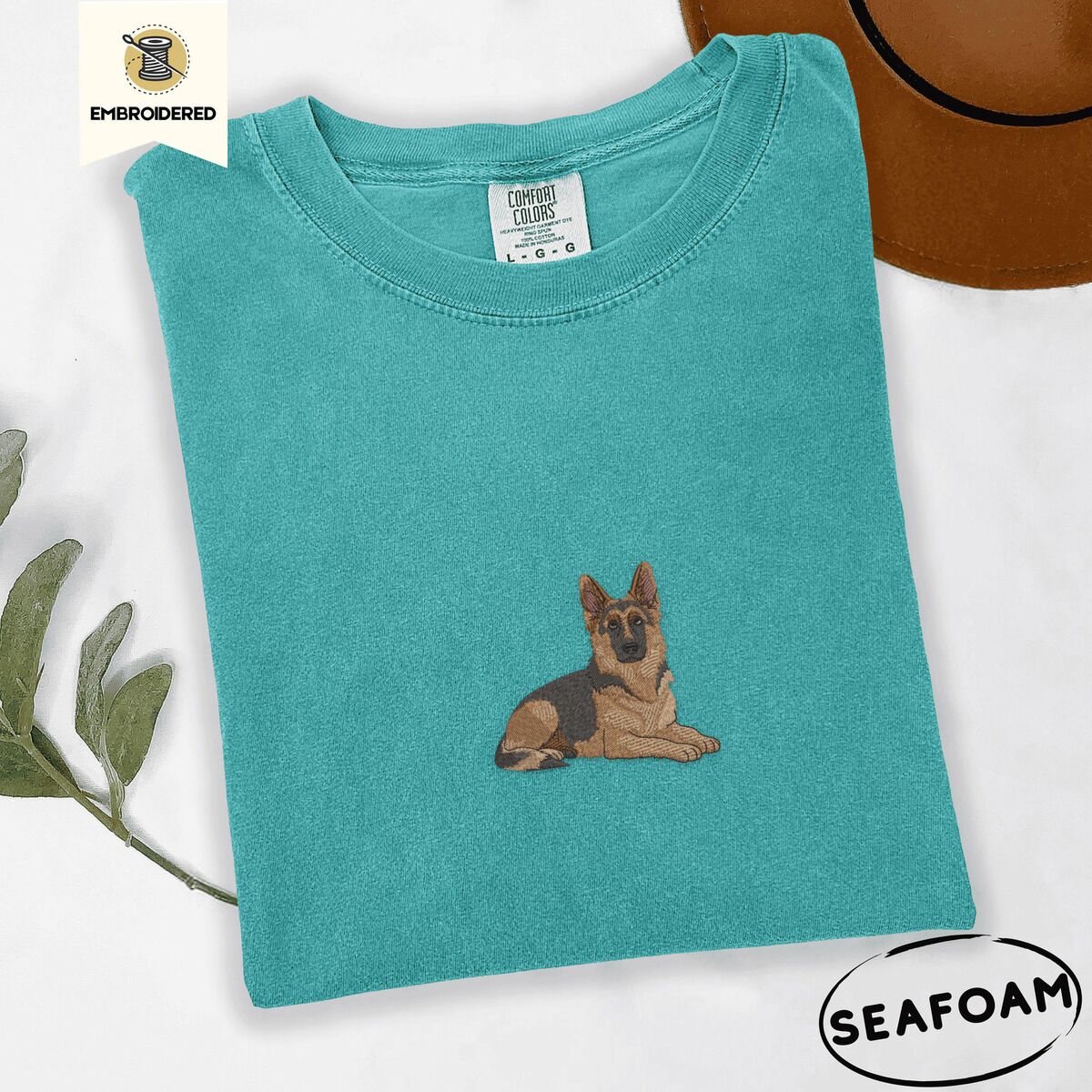 German Shepherd Shirt – Seafoam Seafoam Comfort Colors T-shirt embroidered with a black and tan German shepherd lying down with its ears up and its paws forward