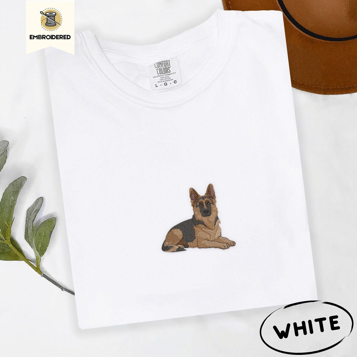 German Shepherd Shirt – White White Comfort Colors T-shirt embroidered with a black and tan German shepherd lying down with its ears up and its paws forward