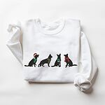 White crewneck sweatshirt laid flat on a white background, embroidered with four black German shepherd silhouettes in a Santa hat, striped scarves and a red bow