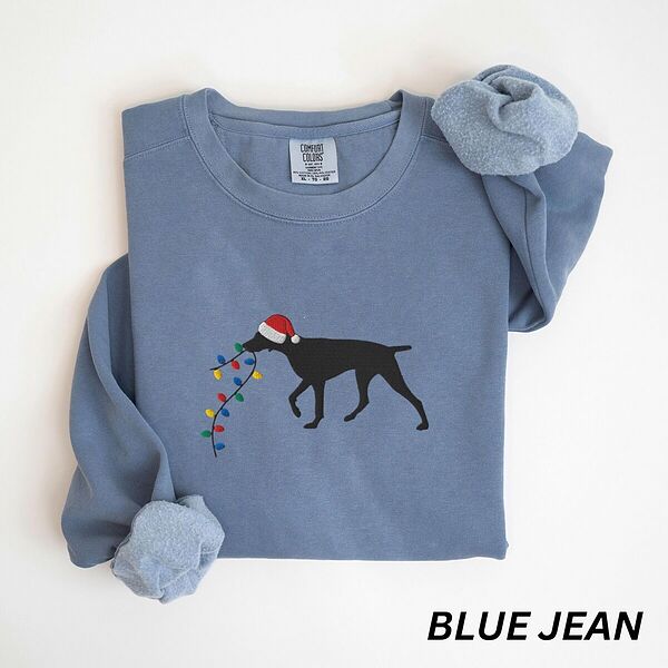 Blue Jean crewneck sweatshirt laid flat, embroidered with a black German shorthaired pointer in a Santa hat carrying Christmas lights