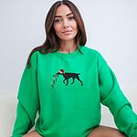Woman in an Irish Green crewneck sweatshirt embroidered with a black German shorthaired pointer in a Santa hat carrying a string of Christmas lights