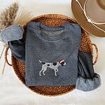 Dark Heather crewneck sweatshirt folded in a wicker basket, embroidered with a black and white ticked German shorthaired pointer in a red Santa hat