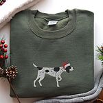 Military Green crewneck sweatshirt laid flat with pine cones, red berries and a grey knit blanket, embroidered with a black and white ticked German shorthaired pointer in a red Santa hat
