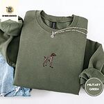Military Green crewneck sweatshirt folded with light jeans and a silver chain necklace, embroidered with a standing liver and white German shorthaired pointer in a tan collar