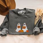 Dark Heather crewneck sweatshirt folded with a brown felt hat and dried bunny tail grass, embroidered with two dogs in white ghost sheets holding jack-o'-lantern buckets among pumpkins, with bats and stars