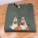 Military Green crewneck sweatshirt folded on a wooden table, embroidered with two dogs in white ghost sheets holding jack-o'-lantern buckets among pumpkins, with bats and stars