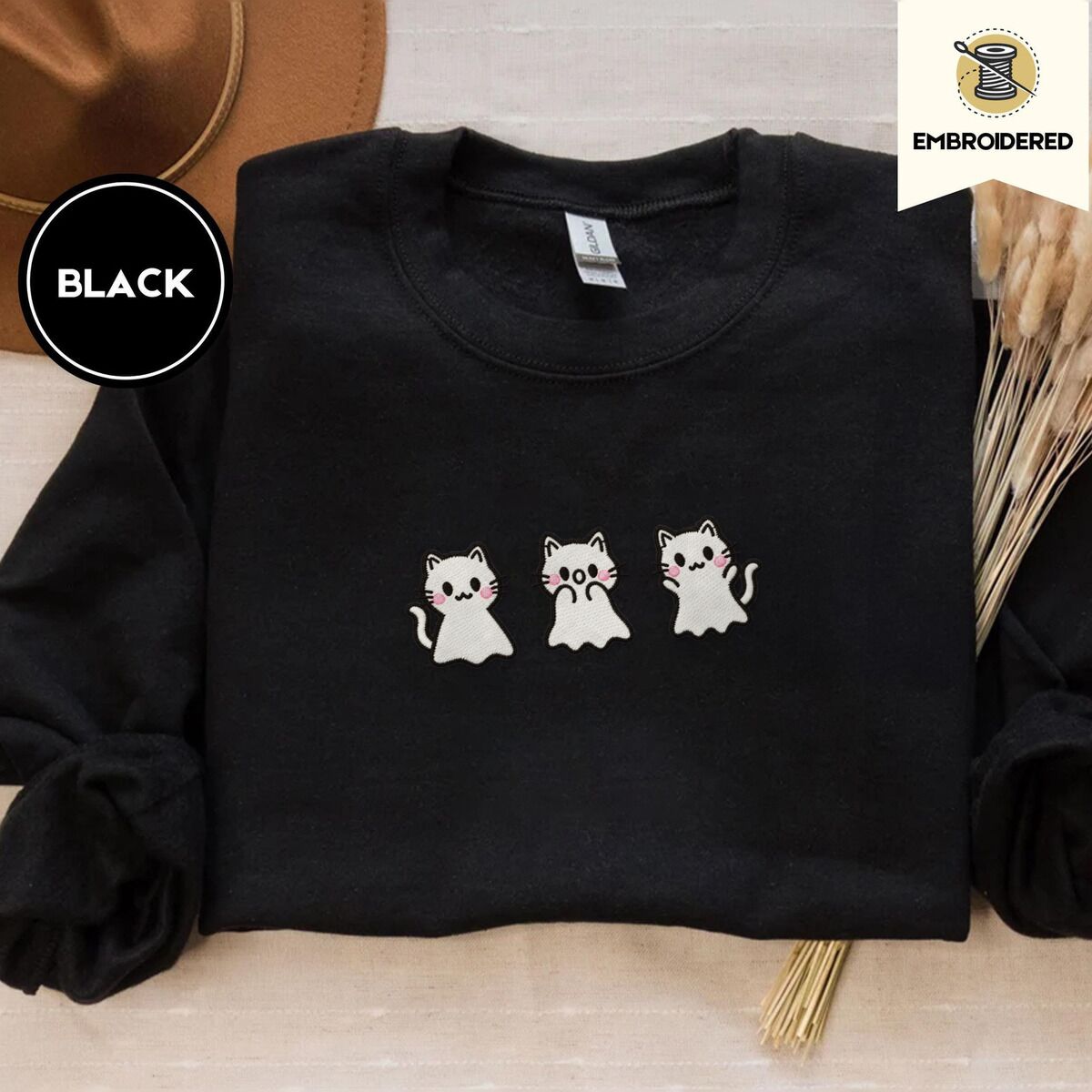 Ghost Kitten Sweatshirt – Black Black crewneck sweatshirt with a brown felt hat and dried bunny tail grass, embroidered with three white ghost kittens with pink cheeks and black outlines