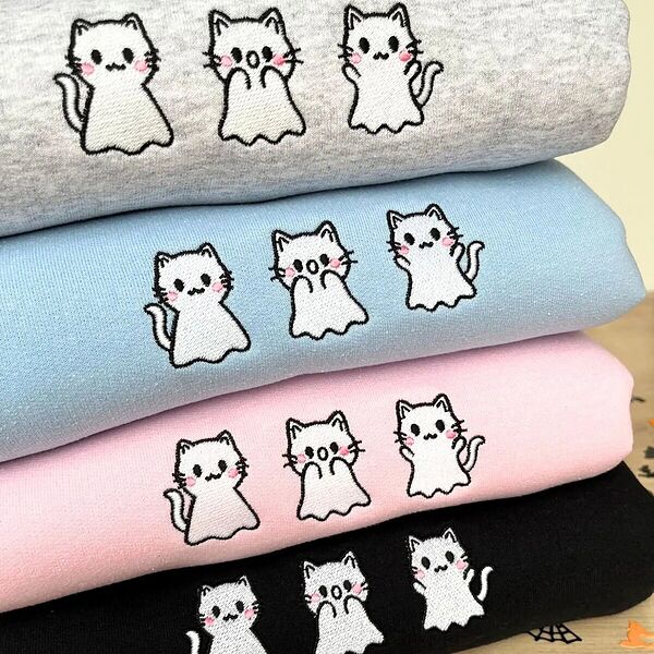 Four crewneck sweatshirts stacked in heather grey, light blue, light pink and black, each embroidered with three white ghost kittens with pink cheeks across the chest