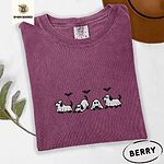 Berry Comfort Colors T-shirt embroidered with four puppies in white ghost sheets with black floppy ears and tails under three flying black bats
