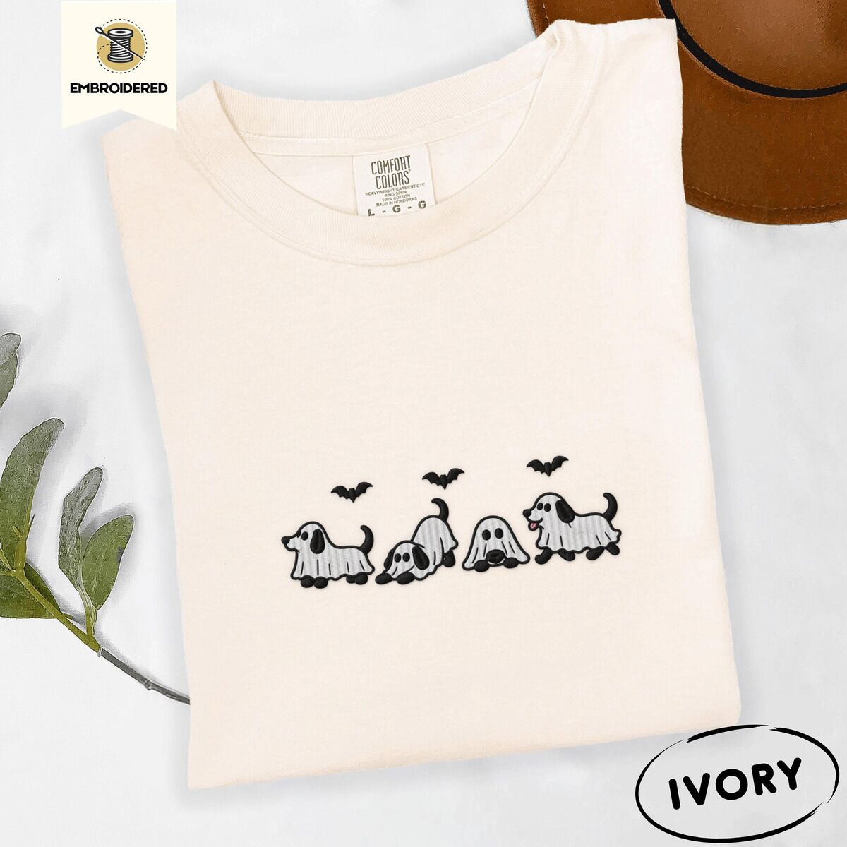 Ghost Puppy Shirt – Ivory Ivory Comfort Colors T-shirt embroidered with four puppies in white ghost sheets with black floppy ears and tails under three flying black bats
