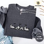 Dark Heather crewneck sweatshirt folded with ripped jeans and a silver chain necklace, embroidered with four puppies in white ghost sheets with black floppy ears and tails under three flying black bats