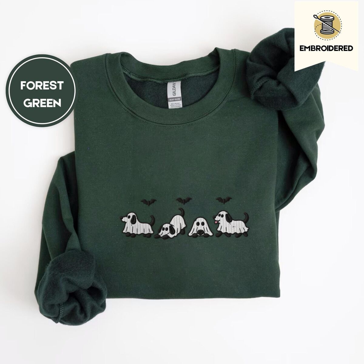 Ghost Puppy Sweatshirt – Forest Green Forest Green crewneck sweatshirt folded on a white background, embroidered with four puppies in white ghost sheets with black floppy ears and tails under three flying black bats