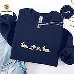 Navy crewneck sweatshirt folded with ripped jeans and a silver chain necklace, embroidered with four puppies in white ghost sheets with black floppy ears and tails under three flying black bats