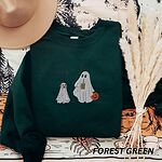 Forest Green crewneck sweatshirt laid flat with a brown hat and pampas grass, embroidered with a ghost sipping iced coffee and carrying a jack-o'-lantern pail while walking a little yellow lab in a ghost sheet on a leash