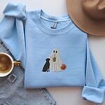 Light Blue crewneck sweatshirt laid flat beside jeans and a coffee cup, embroidered with a ghost lab mom sipping iced coffee and carrying a jack-o'-lantern pail, with a black lab sitting against her
