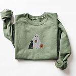 Military Green crewneck sweatshirt laid flat on a white background, embroidered with a ghost lab mom sipping iced coffee and carrying a jack-o'-lantern pail, with a black lab sitting against her