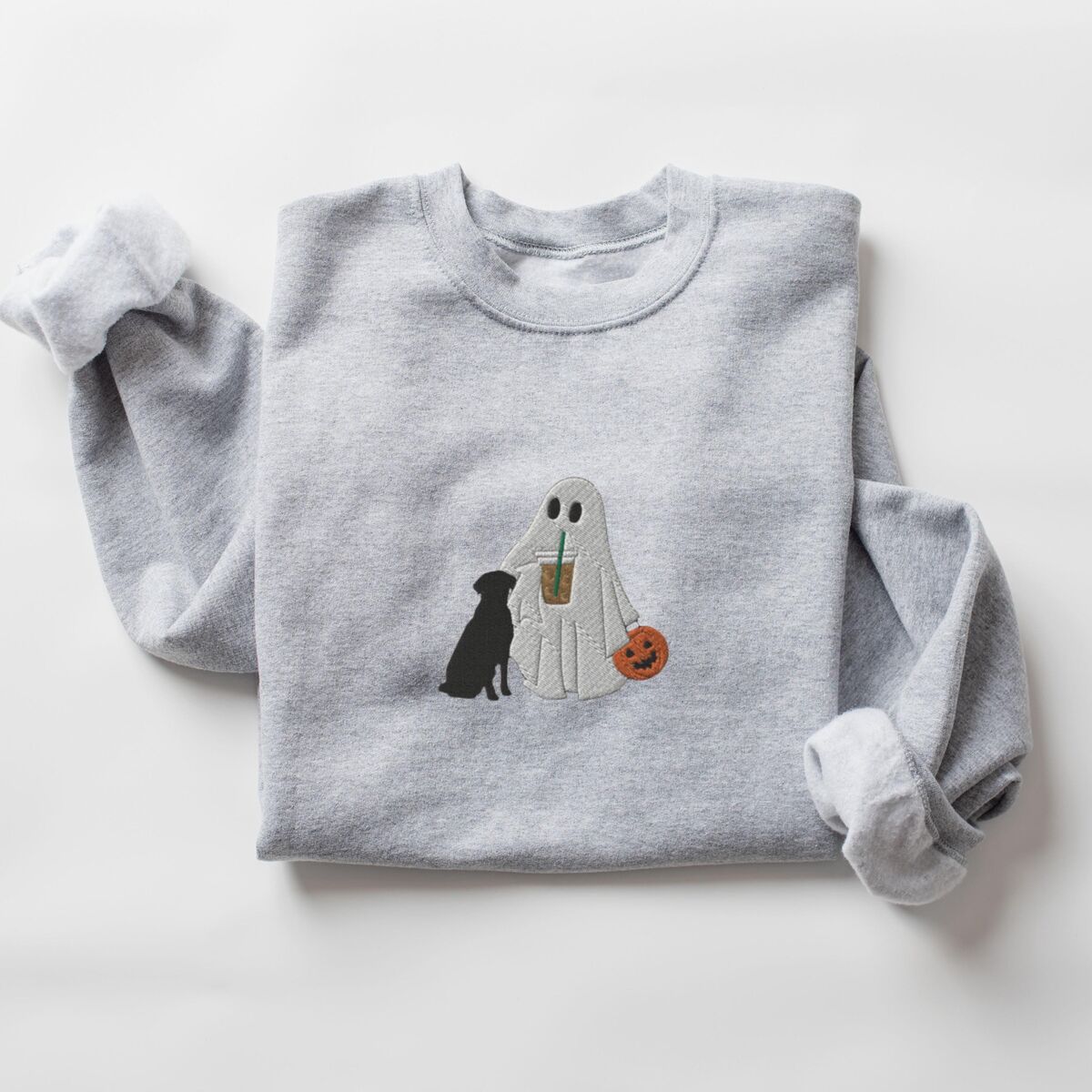 Ghost with Black Lab Sweatshirt - Sport Grey Sport Grey crewneck sweatshirt laid flat on a white background, embroidered with a ghost lab mom sipping iced coffee and carrying a jack-o'-lantern pail, with a black lab sitting against her
