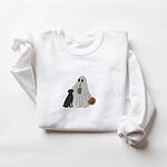 White crewneck sweatshirt laid flat on a white background, embroidered with a ghost lab mom sipping iced coffee and carrying a jack-o'-lantern pail, with a black lab sitting against her