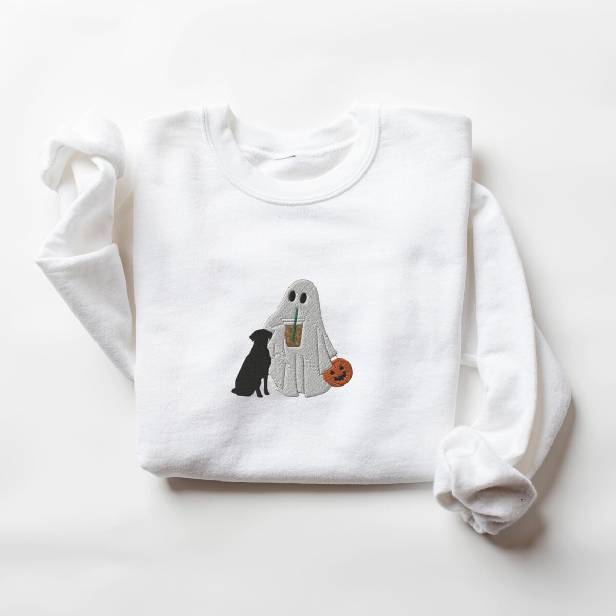 Ghost with Black Lab Sweatshirt - White White crewneck sweatshirt laid flat on a white background, embroidered with a ghost lab mom sipping iced coffee and carrying a jack-o'-lantern pail, with a black lab sitting against her