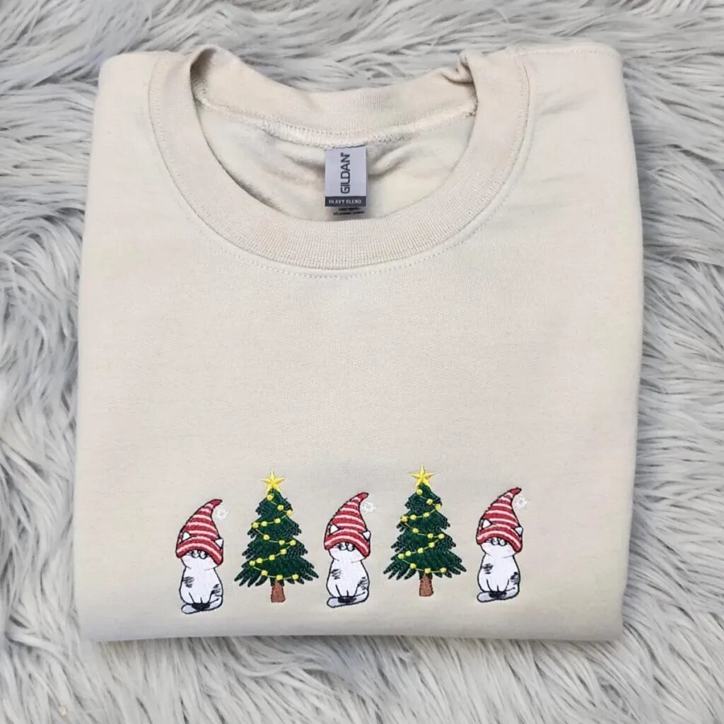 Gnome cat sweatshirt in Sand with three white cats in striped gnome hats and two Christmas trees across the chest