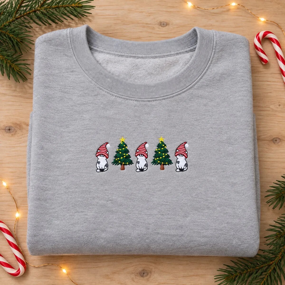 Gnome Cat Sweatshirt – Sport Grey Gnome cat sweatshirt in Sport Grey laid flat with pine sprigs, candy canes and fairy lights