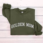 Military Green crewneck sweatshirt laid flat on wood, embroidered with GOLDEN MOM in arched white varsity letters