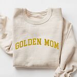 Sand crewneck sweatshirt laid flat, embroidered with GOLDEN MOM in arched mustard gold varsity letters