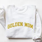 White crewneck sweatshirt laid flat, embroidered with GOLDEN MOM in arched mustard gold varsity letters