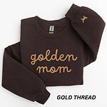 Dark Chocolate crewneck sweatshirt laid flat, embroidered with golden mom in gold script across the chest and a small golden retriever silhouette on the cuff